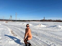 Fille nue russe sur la route et le village d'hiver